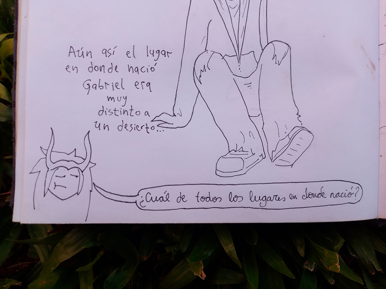 Photo of an open notebook showing a cartoon of myself saying, 'Even so, the place where Gabriel was born was very different from a desert...' and another character below saying, 'Which of all the places where he was born?'
